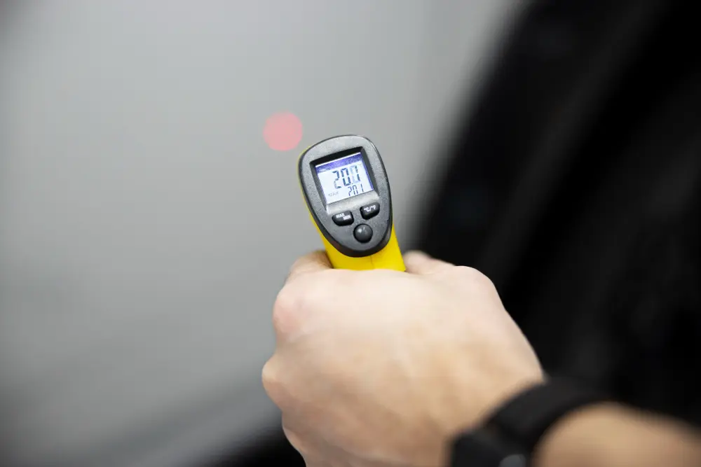 Mão segurando termômetro digital infravermelho