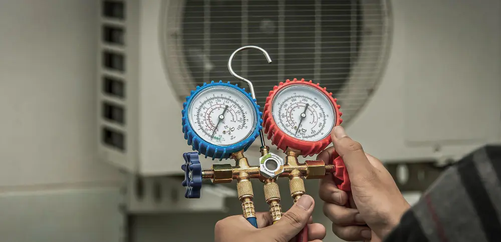 Mãos segurando manômetro com ar condicionado em desfoque ao fundo